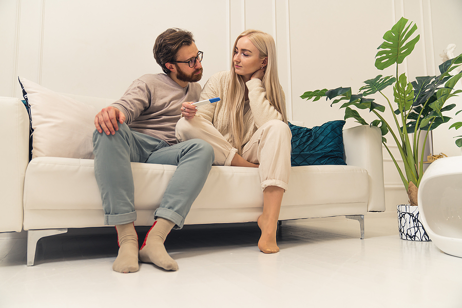 Couple sitting on couch looking at pregnancy test