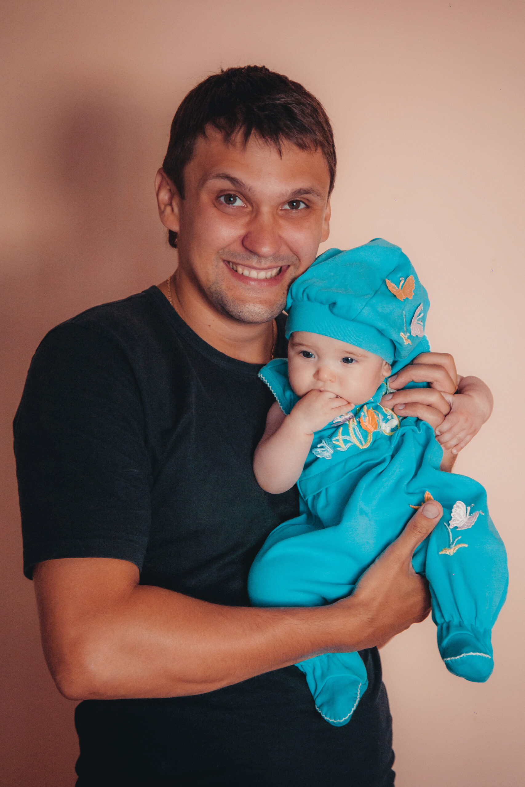 Baby On The Hands Of Father. Man And Child In A Black And Blue latino man holding baby