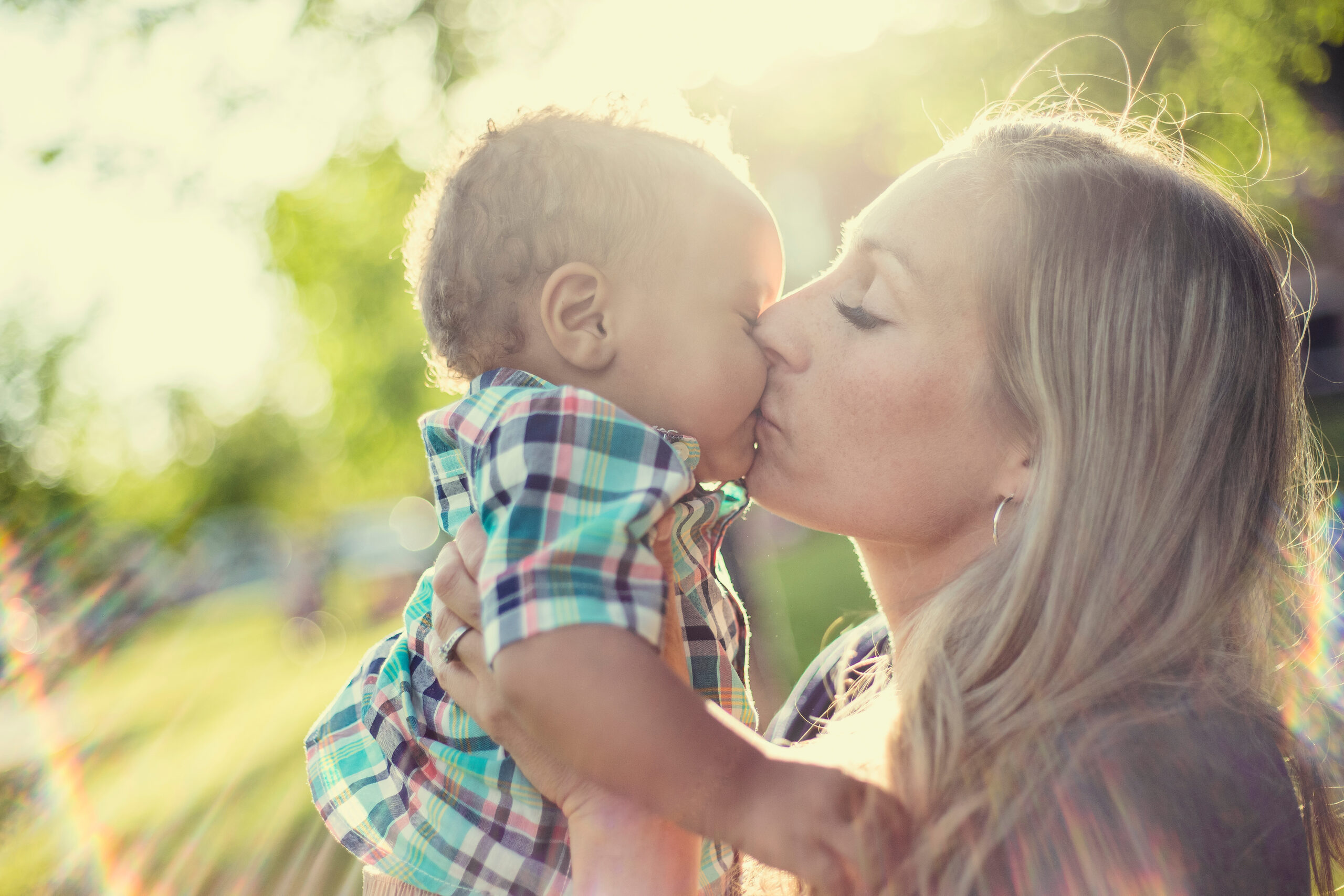 woman kissing toddler on head