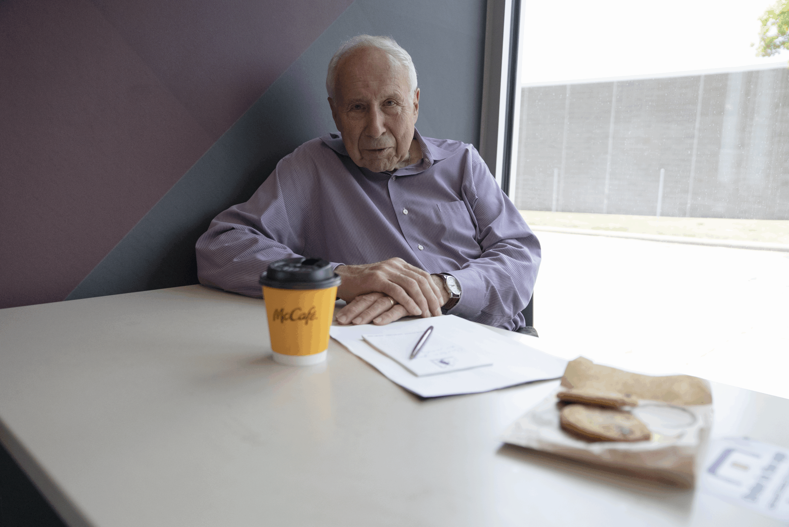Carl sitting at McDonalds with a coffee cup and cookie.